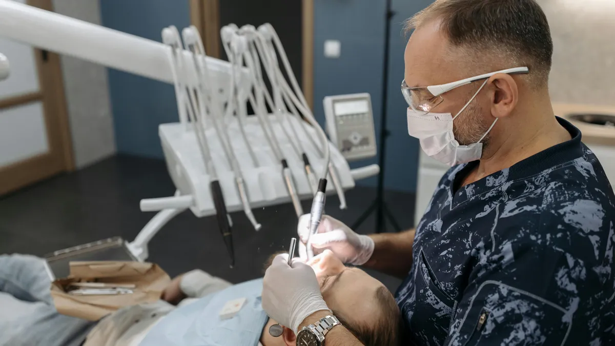 Dentist in scrubs adjusting overhead light while caring for patient at Prosper TX dental office